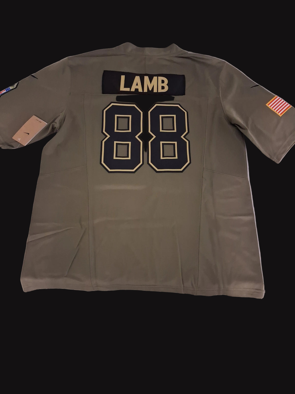 An olive drab short-sleeve sports jersey laid flat on a white surface, showing the back with a black name patch reading 'LAMB' and large black number 88 outlined in gold. A small American flag patch is visible on the sleeve.